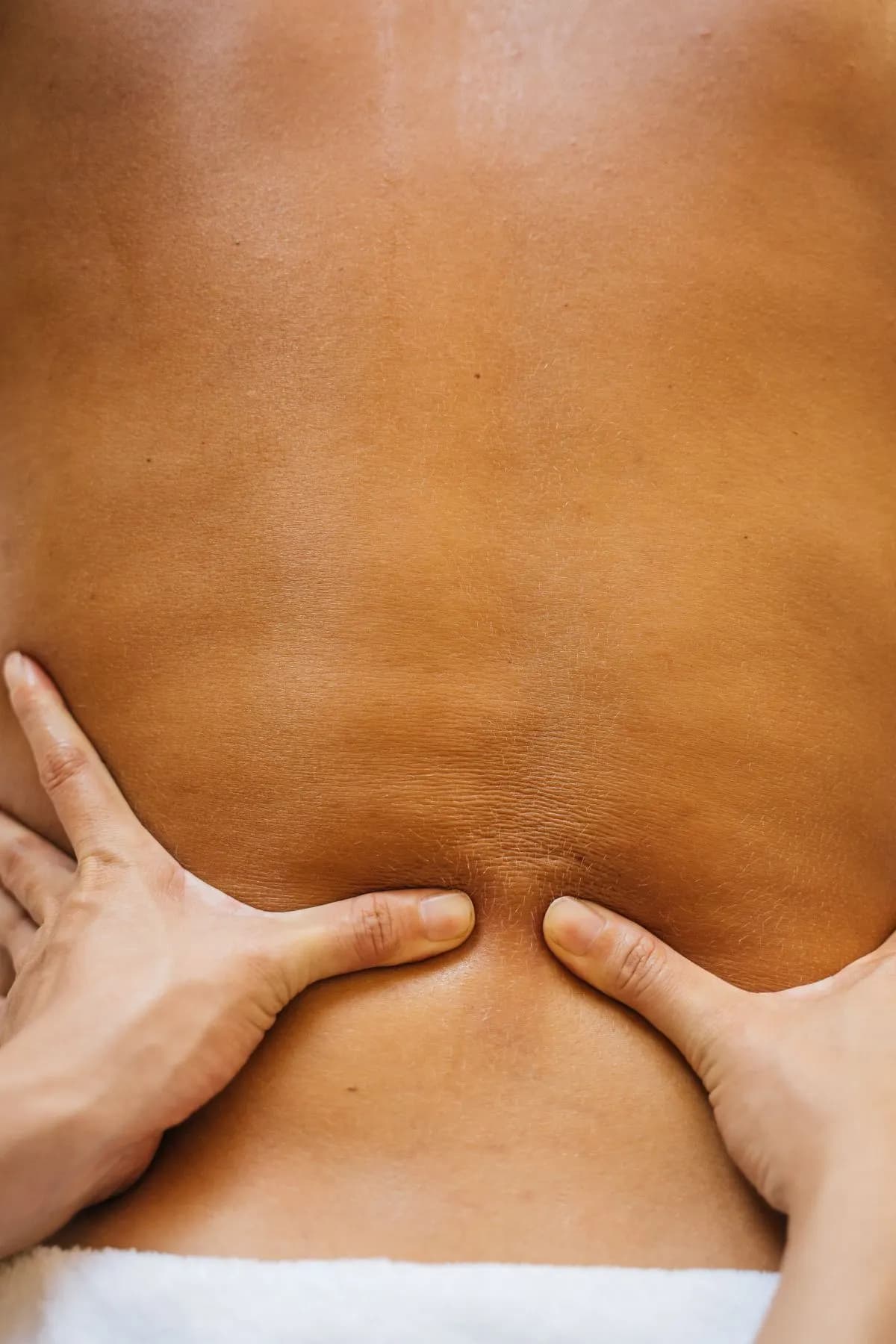 Therapist pressing thumbs into a client's lower back