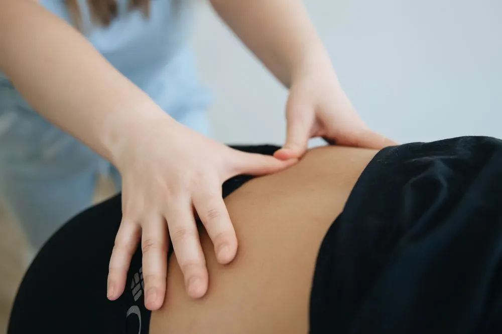Hand pressing firmly on a client's back in a clinical, therapeutic style