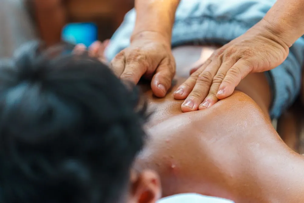 Close-up of a therapist's hands pressing on a shoulder blade